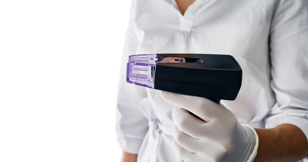 A person in a white coat and gloves holding a Morpheus8 aesthetic treatment device in Astoria, NY.